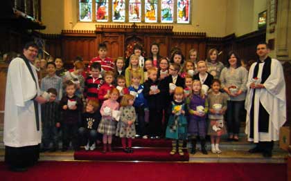 Pictured in St Anne’s Church  Revd. Andrew Forster and Revd. Stephen McElhinney with the children displaying their gifts.